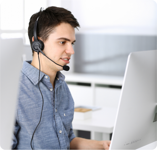 Customer service representative assisting clients with headset while working on a computer.